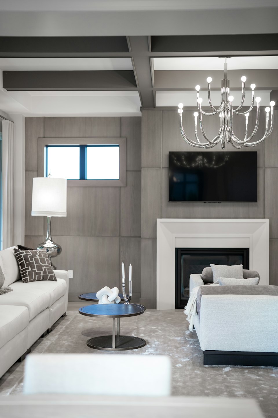 Modern living room with white and grey sofas and a fireplace.