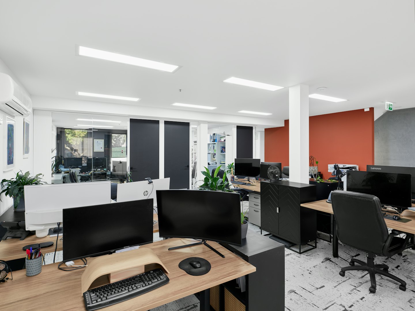 Empty modern office workstations with plants and accent walls.
